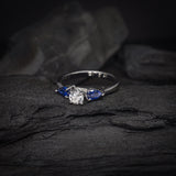 Anillo de compromiso con diamante natural central de .30ct corte brillante con certificación GIA y 2 zafiros naturales realizado en oro blanco de 14k