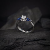 Anillo de compromiso con diamante natural central de .30ct corte brillante con certificación GIA y 2 zafiros naturales realizado en oro blanco de 14k