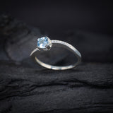 Anillo de compromiso con topacio natural de .50ct corte brillante y cristales laterales elaborado en plata .925