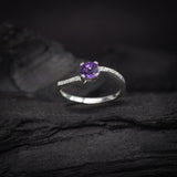 Anillo de compromiso con amatista natural de .50ct corte brillante y cristales laterales elaborado en plata .925