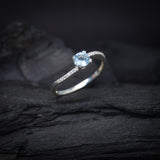 Anillo de compromiso con topacio natural de .50ct corte brillante y cristales laterales elaborado en plata .925