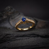 Anillo de compromiso con zafiro natural de .50ct corte brillante y 24 cristales laterales elaborado en oro amarillo de 14k