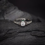 Anillo de compromiso con diamante natural central de .40ct corte brillante con certificación GIA, 2 esmeraldas y 12 diamantes naturales laterales elaborado en oro blanco de 14k