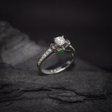 Anillo de compromiso con diamante natural central de .40ct corte brillante con certificación GIA, 2 esmeraldas y 12 diamantes naturales laterales elaborado en oro blanco de 14k