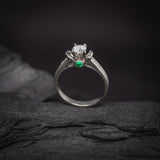 Anillo de compromiso con diamante natural central de .40ct corte brillante con certificación GIA, 2 esmeraldas y 12 diamantes naturales laterales elaborado en oro blanco de 14k