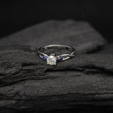 Anillo de compromiso con diamante natural de .20ct corte brillante y 2 zafiros naturales laterales elaborado en oro blanco de 14k