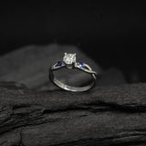 Anillo de compromiso con diamante natural de .20ct corte brillante y 2 zafiros naturales laterales elaborado en oro blanco de 14k