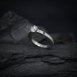 Anillo de compromiso con diamante natural central de .50ct corte brillante con certificación GIA, 2 zafiros naturales y 18 diamantes naturales laterales en oro blanco de 14k