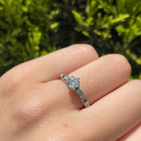 Anillo de compromiso con diamante natural central de .50ct corte brillante con certificación GIA, 2 zafiros naturales y 18 diamantes naturales laterales en oro blanco de 14k