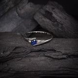 Anillo de compromiso con zafiro natural de .20ct corte brillante y 2 cristales laterales elaborado en plata .930