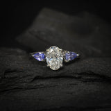 Anillo de compromiso con diamante de laboratorio de 1.0ct corte oval con certificado IGI y 2 tanzanitas naturales laterales elaborado en oro blanco de 14k