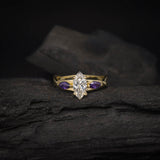 Anillo de compromiso con diamante natural de .70ct corte marquise con certificación GIA y 2 zafiros morados naturales laterales elaborado en oro amarillo de 14k