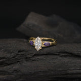 Anillo de compromiso con diamante natural de .70ct corte marquise con certificación GIA y 2 zafiros morados naturales laterales elaborado en oro amarillo de 14k