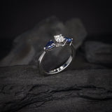 Anillo de compromiso con diamante natural central de .30ct corte brillante con certificación GIA y 2 zafiros naturales realizado en oro blanco de 14k