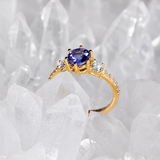 Anillo de compromiso con tanzanita natural de .80ct corte brillante y 12 moissanitas laterales elaborado en oro amarillo de 14k