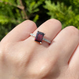 Anillo de compromiso con granate natural corte esmeralda y 12 diamantes laterales elaborado en plata .970