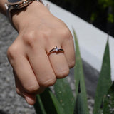 Anillo de compromiso con moissanita de .20ct corte brillante y 2 cristales laterales elaborado en oro rosa de 10k