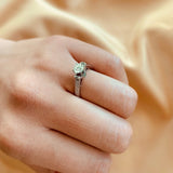 Anillo de compromiso con diamante natural central de .40ct corte brillante con certificación GIA, 2 esmeraldas y 12 diamantes naturales laterales elaborado en oro blanco de 14k