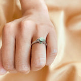 Anillo de compromiso con diamante natural central de .40ct corte brillante con certificación GIA, 2 esmeraldas y 12 diamantes naturales laterales elaborado en oro blanco de 14k