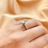 Anillo de compromiso con diamante natural central de .40ct corte brillante con certificación GIA, 2 esmeraldas y 12 diamantes naturales laterales elaborado en oro blanco de 14k