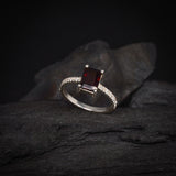 Anillo de compromiso con granate natural corte esmeralda y 12 diamantes laterales elaborado en plata .970