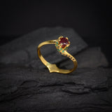 Anillo de compromiso con rubí natural central corte brillante, esmeraldas naturales y diamantes negros  naturales laterales elaborado en oro amarillo de 14k