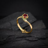 Anillo de compromiso con rubí natural central corte brillante, esmeraldas naturales y diamantes negros  naturales laterales elaborado en oro amarillo de 14k