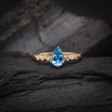Anillo de compromiso con topacio corte gota y 6 diamantes laterales elaborado en oro amarillo de 14 kilates