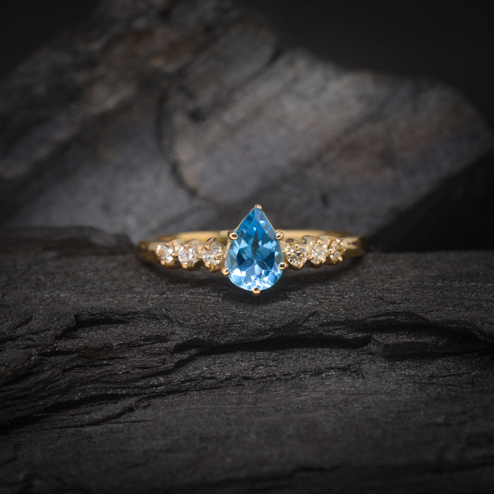 Anillo de compromiso con topacio corte gota y 6 diamantes laterales elaborado en oro amarillo de 14 kilates