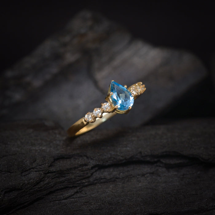 Anillo de compromiso con topacio corte gota y 6 diamantes laterales elaborado en oro amarillo de 14 kilates