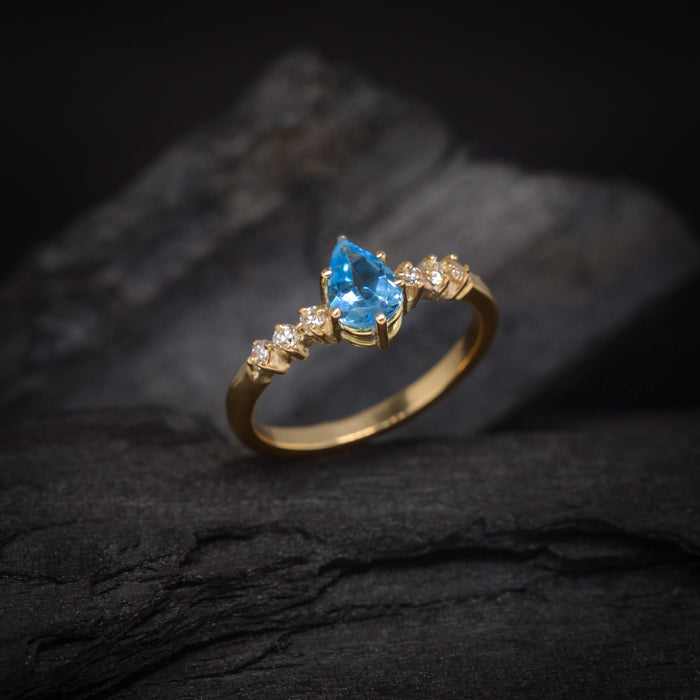 Anillo de compromiso con topacio corte gota y 6 diamantes laterales elaborado en oro amarillo de 14 kilates
