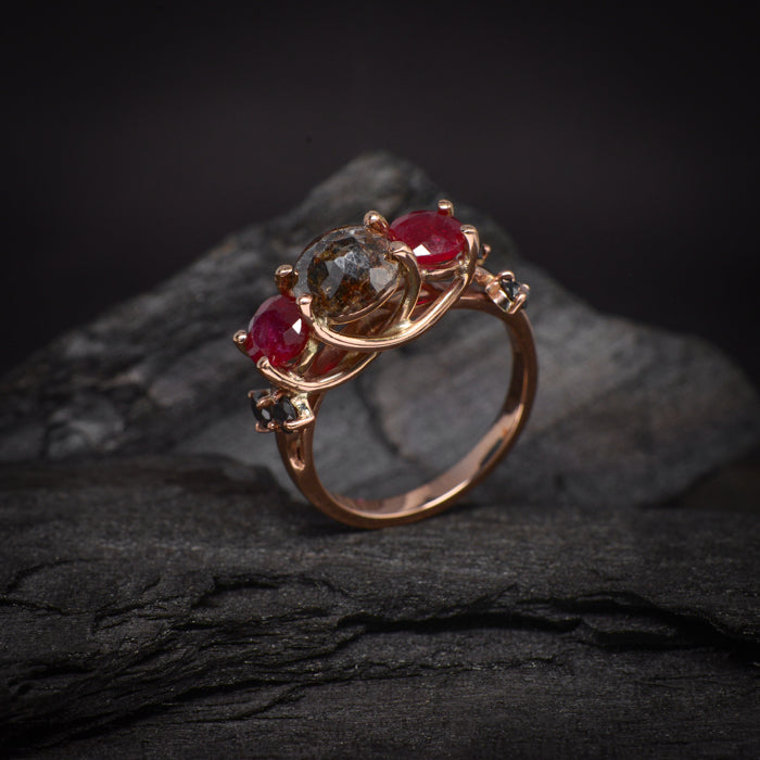 Anillo de compromiso con diamante natural "sal y pimienta" central de 1.20ct, 2 rubíes naturales y 4 diamantes negros naturales elaborado en oro rosa de 14 kilates