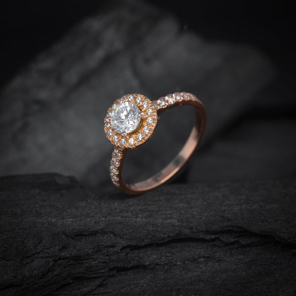 Anillo de compromiso con diamante natural central de .50ct y cristales laterales elaborado en oro rosa de 14 kilates