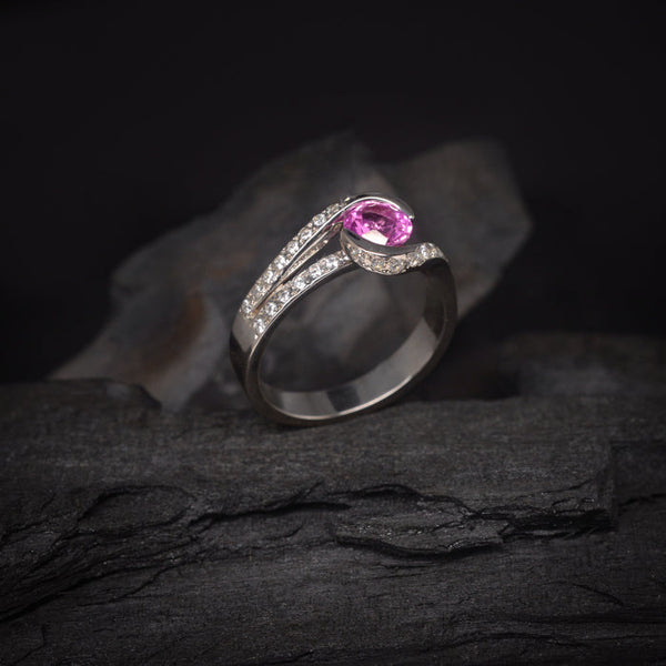 Anillo de compromiso con zafiro rosa de .50ct y cristales laterales elaborado en oro blanco de 18 kilates