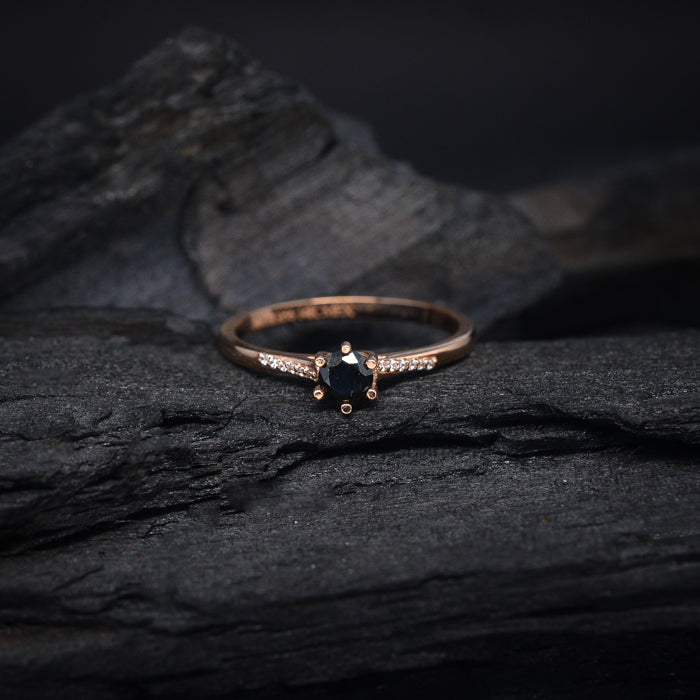 Anillo de compromiso con diamante negro natural central de .40ct y cristales laterales elaborado en oro rosa de 14 kilates