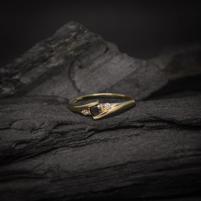 Anillo de compromiso con diamante negro natural de .20ct y cristales laterales elaborado en oro amarillo de 10 kilates