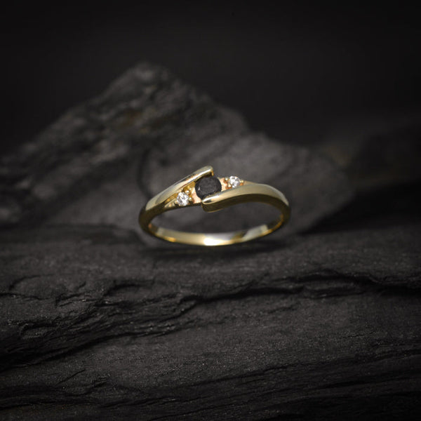Anillo de compromiso con diamante negro natural de .20ct y cristales laterales elaborado en oro amarillo de 14 kilates