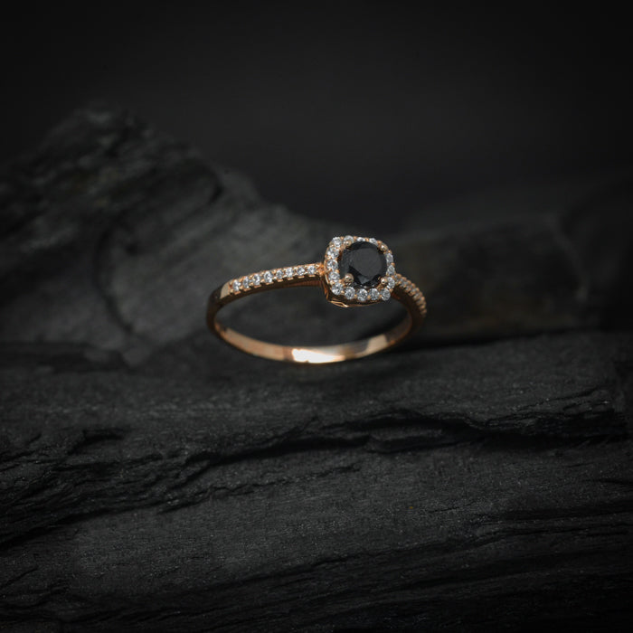 Anillo de compromiso con diamante negro natural central de .30ct y cristales laterales elaborado en oro rosa de 14 kilates