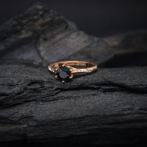 Anillo de compromiso con diamante negro natural de .70ct y cristales laterales elaborado en oro rosa de 14 kilates