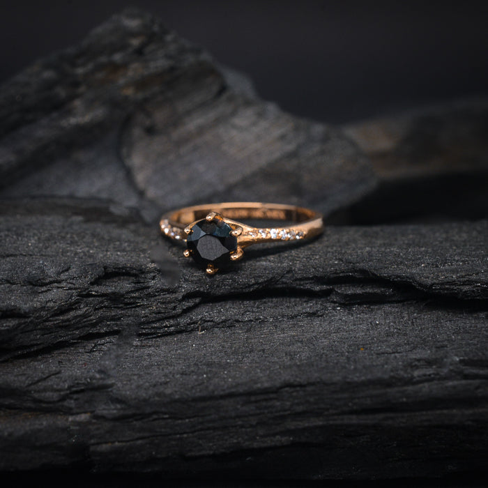 Anillo de compromiso con diamante negro natural central de .70ct y cristales laterales elaborado en oro rosa de 14 kilates