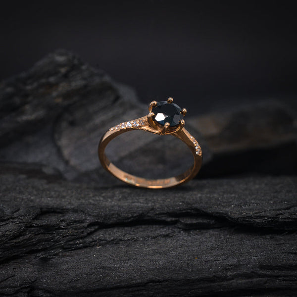 Anillo de compromiso con diamante negro natural de .70ct y cristales laterales elaborado en oro rosa de 14 kilates
