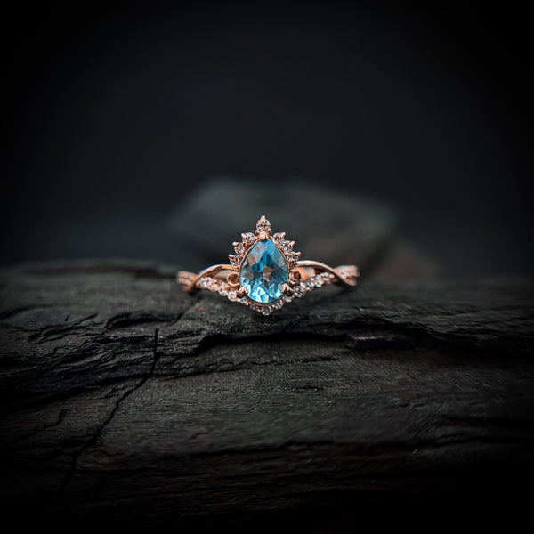 Anillo de compromiso con topacio natural de .80ct corte gota y diamantes naturales laterales elaborado en oro rosa de 14k