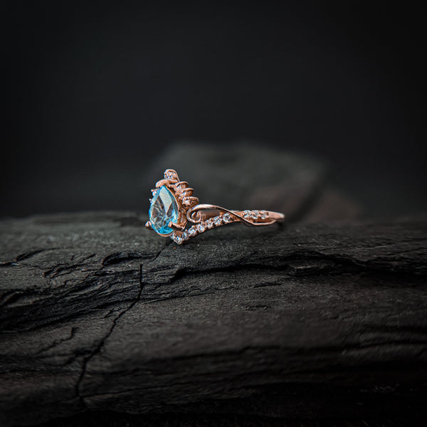 Anillo de compromiso con topacio natural de .80ct corte gota y diamantes naturales laterales elaborado en oro rosa de 14k