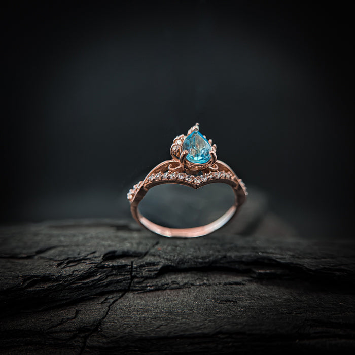 Anillo de compromiso con topacio natural de .80ct corte gota y diamantes naturales laterales elaborado en oro rosa de 14k