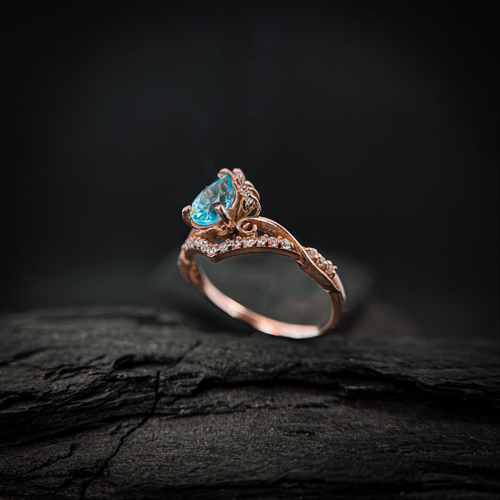 Anillo de compromiso con topacio natural de .80ct corte gota y diamantes naturales laterales elaborado en oro rosa de 14k