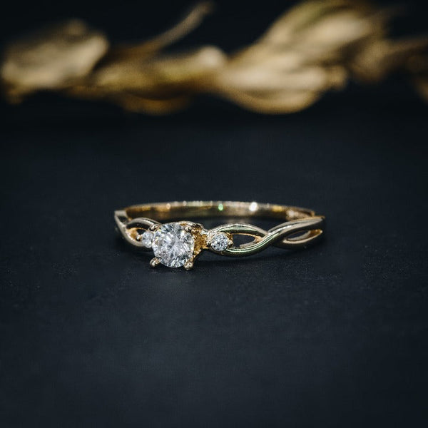 Anillo de compromiso con diamante de laboratorio de .50ct y cristales laterales elaborado en oro amarillo de 14 kilates