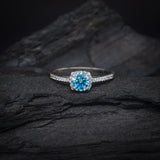 Anillo de compromiso con moissanita azul de .50ct con certificado GRA y 32 diamantes laterales elaborado en oro blanco de 18 kilates