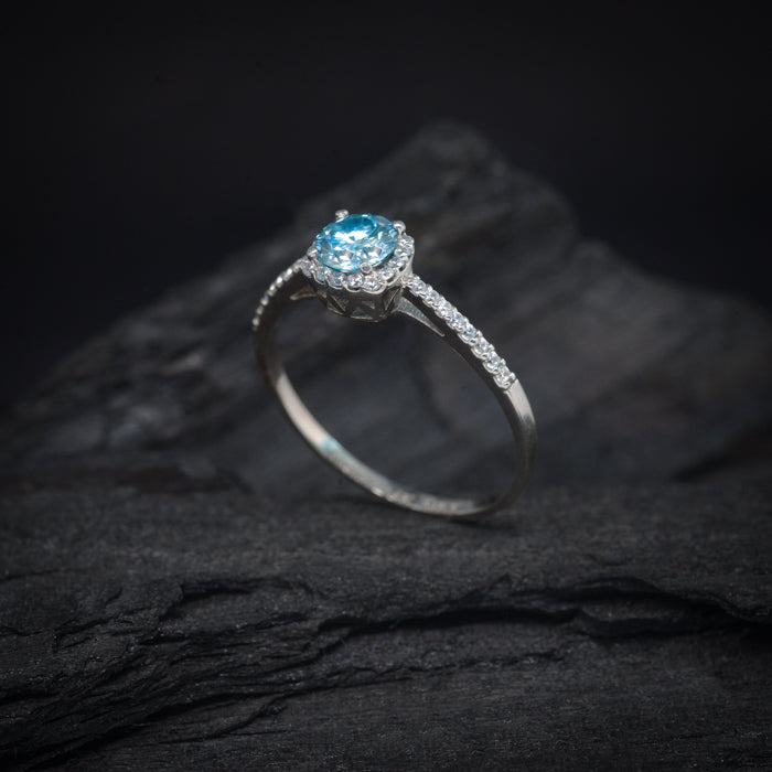 Anillo de compromiso con moissanita azul de .50ct con certificado GRA y 32 diamantes laterales elaborado en oro blanco de 18 kilates