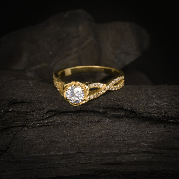 Anillo de compromiso con diamante natural central de .50ct y cristales laterales elaborado en oro amarillo de 14 kilates