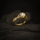 Anillo de compromiso con diamante natural central de .50ct y cristales laterales elaborado en oro amarillo de 14 kilates